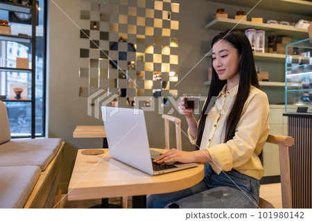 Contented young woman using her laptop during the coffee break 101980142