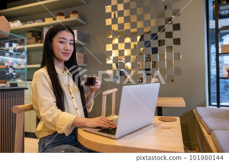 Pleased remote worker drinking a caffeinated beverage in a cafe 101980144