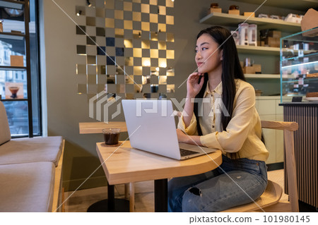 Asian woman daydreaming at the laptop in a coffee shop 101980145