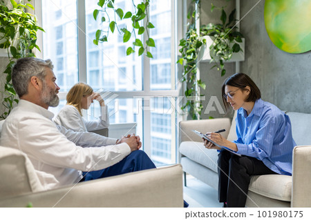 Psychologist having a sessiona with a couple and making notes Psychologist having a sessiona with a couple and making notes 101980175