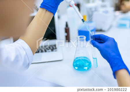 Scientist examining liquid in test tube in laboratory 101980222