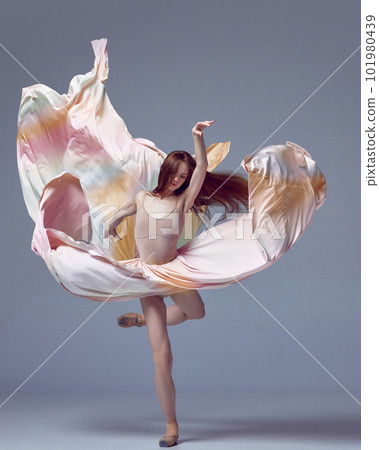 Beautiful ballerina dancing elegant, grace movement with flying fabric over grey studio background. Dancer in motion 101980439