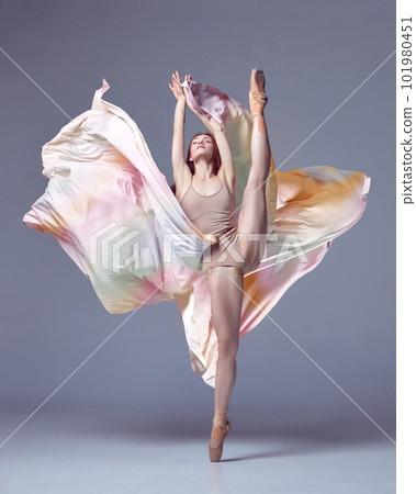 One grace ballerina wearing rainbow dress emotional dancing with fabric over grey studio background. Aesthetic of classical dance 101980451