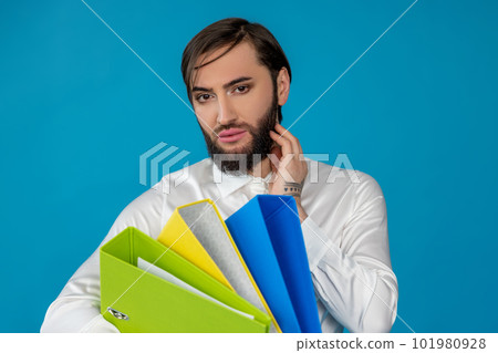 Elegant transsexual guy manager with beard holding multicolored paper folders doing office work Elegant transsexual guy manager with beard holding multicolored paper folders doing office work 101980928
