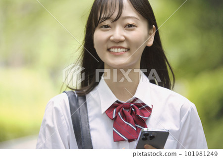 一個帶著智能手機的女高中生，穿著新綠色的衣服 101981249