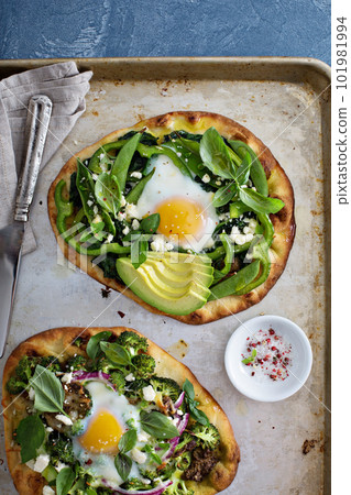 Breakfast pizza with baked egg and greens 101981994