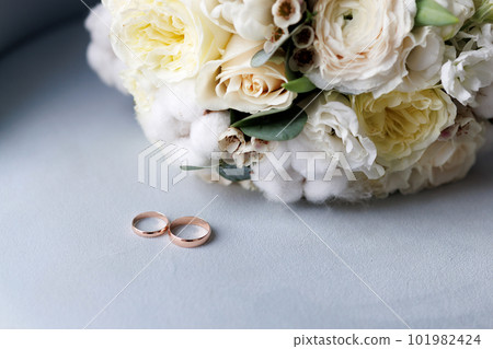 A wedding bouquet and two golden wedding rings 101982424