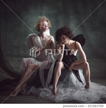 Portrait of two women, queens, angel and demon against dark, green, vintage background. Balance of human being 101983780