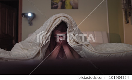young girl watching a movie on a projector, rejoices showing emotions. 101984334