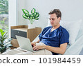 Caucasian patient using laptop in hospital room. man sick patient lying in a hospital bed 101984459