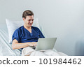 Caucasian patient using laptop in hospital room. man sick patient lying in a hospital bed 101984462