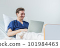 Caucasian patient using laptop in hospital room. man sick patient lying in a hospital bed 101984463