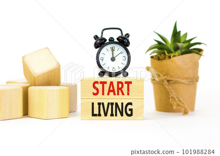 Start living symbol. Concept words Start living on beautiful wooden block. Beautiful white table white background. Black alarm clock. Business and Start living concept. Copy space. Start living symbol. Concept words Start living on beautiful wooden block. Beautiful white table white background. Black alarm clock. Business and Start living concept. Copy space. 101988284
