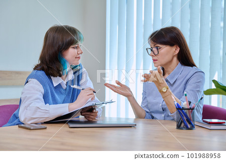 Woman social worker, mentor interviewing, talking to young teen female in office 101988958