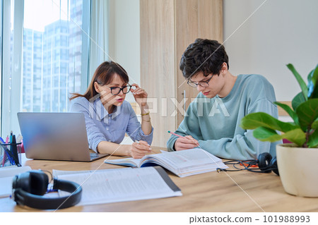 Female tutor teaching college student guy, in classroom at desk Female tutor teaching college student guy, in classroom at desk 101988993