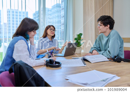 College students with teacher sitting at desk in classroom studying languages, sciences 101989004