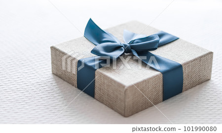 Holiday present and luxury online shopping delivery, wrapped linen gift box with blue ribbon on bed in bedroom, chic countryside style Holiday present and luxury online shopping delivery, wrapped linen gift box with blue ribbon on bed in bedroom, chic countryside style 101990080