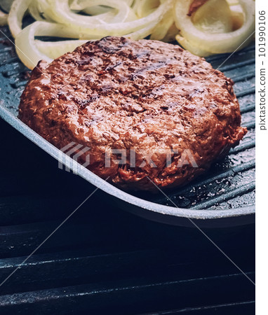 Cooking minced beef burger on cast iron grill skillet outdoors, red meat on frying pan, grilling food in the garden, English countryside living Cooking minced beef burger on cast iron grill skillet outdoors, red meat on frying pan, grilling food in the garden, English countryside living 101990106