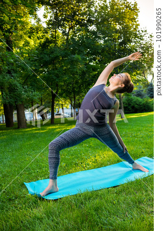Young woman doing yoga exercises in the summer city park. 101990265