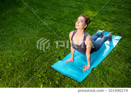 Young woman doing yoga exercises in the summer city park. 101990274