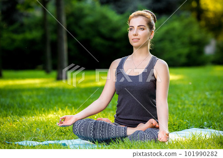 Young woman doing yoga exercises in the summer city park. 101990282