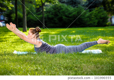 Young woman doing yoga exercises in the summer city park. 101990355