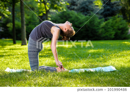Young woman doing yoga exercises in the summer city park. 101990486