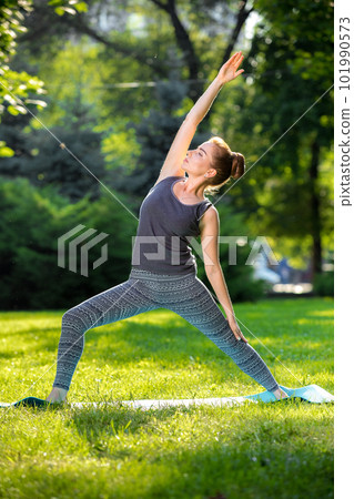 Young woman doing yoga exercises in the summer city park. 101990573