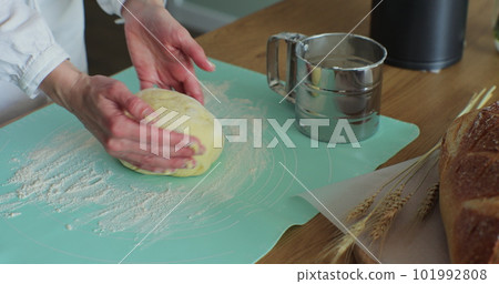 Woman kneading the dough in the kitchen. Cooking at home, enjoying hobby. Making hand-made bread. Woman kneading the dough in the kitchen. Cooking at home, enjoying hobby. Making hand-made bread. 101992808