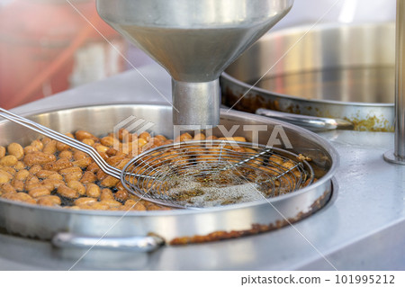The process of cooking lokma, the cook cooks lokma in a deep fryer. Industrial production of a popular Middle Eastern dessert made from deep-fried dough balls. Little donuts. 101995212
