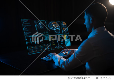 A caucasian man sits in the dark in front of a virtual menu and types on a keyboard. human brain research. 101995690