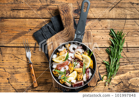 Cooking of fresh seafood mix in a skillet. Wooden background. Top view 101997848