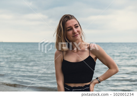 Young woman standing on blurred beachside background. Attractive female enjoying walking the sea shore. travel and active lifestyle concept. Springtime. Relaxation, youth, love, lifestyle solitude Young woman standing on blurred beachside background. Attractive female enjoying walking the sea shore. travel and active lifestyle concept. Springtime. Relaxation, youth, love, lifestyle solitude 102001234