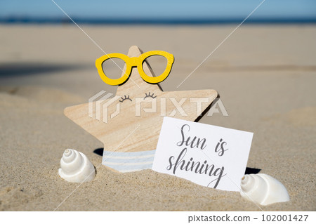 SUN IS SHINING text on paper greeting card on background of funny starfish in glasses summer vacation decor. Sandy beach sun coast. Holiday concept postcard. Getting away Travel SUN IS SHINING text on paper greeting card on background of funny starfish in glasses summer vacation decor. Sandy beach sun coast. Holiday concept postcard. Getting away Travel 102001427