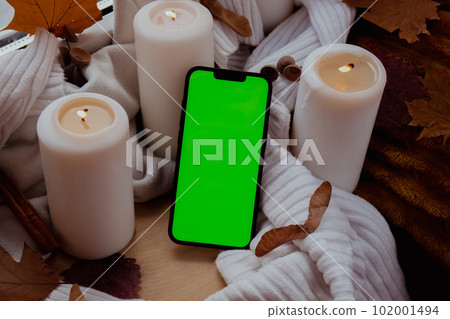 Green screen chromakey mobile phone app copy space on background of aesthetic atmosphere Autumn leaves spices and candle on knitted white sweater in warm yellow lights. Still life. Raining Green screen chromakey mobile phone app copy space on background of aesthetic atmosphere Autumn leaves spices and candle on knitted white sweater in warm yellow lights. Still life. Raining 102001494