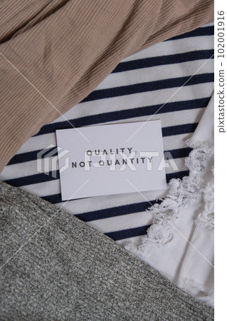 Quality not quantity text on paper note on clothes assortment Second hand sustainable shopping. Capsule minimal wardrobe. Sustainable fashion overconsumption, conscious buying consumption, slow 102001916