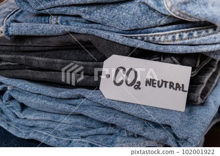 CO2 neutral emission text note on stack of jeans. Ecology nature friendly, climate change, green fuel and earth protect concept. Carbon emission paper recycled label. Natural organic jeans clothing 102001922