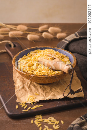 Dry risoni pasta in a ceramic bowl 102002145