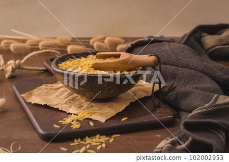 Dry risoni pasta in a ceramic bowl 102002953
