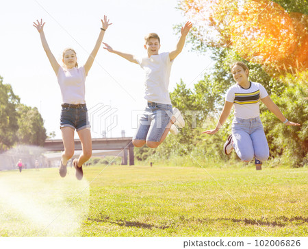 Friendly teenagers jumping together in park 102006826