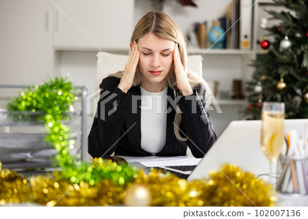 Tired woman bookkeeper in Christmas decorated office 102007136