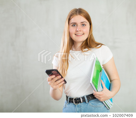 Portrait of female student with a mobile phone in her hand 102007409