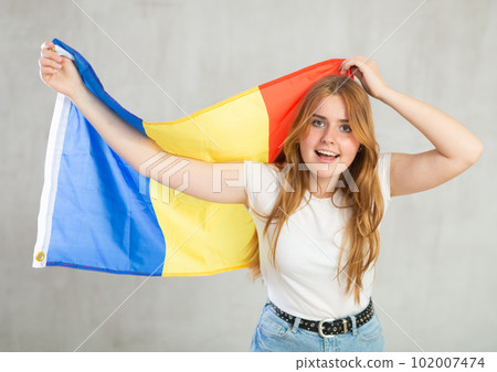 smiling girl in arms raised above head holds canvas of national flag of Romania smiling girl in arms raised above head holds canvas of national flag of Romania 102007474