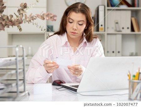 Office worker woman is working at a computer in office Office worker woman is working at a computer in office 102007477