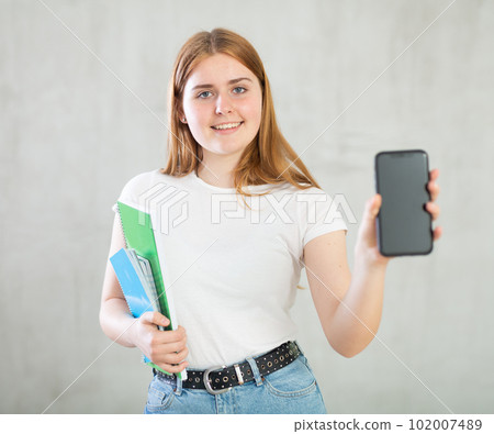 Portrait of positive teen girl holding spiral notepads  102007489