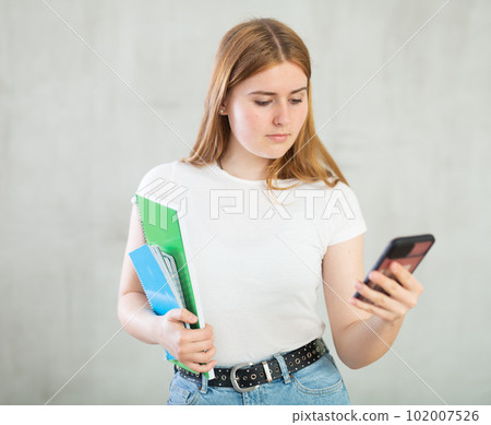 Positive girl student writes a message on the screen of mobile phone 102007526