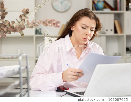 Tired young businesswoman working with documents 102007625