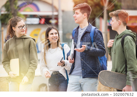 Carefree teen students walking outside school 102007632