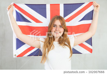 smiling girl in arms raised above head holds canvas of national British flag 102007666