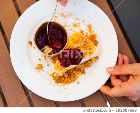 Piece of cheesecake on white plate with raspberry jam on side Piece of cheesecake on white plate with raspberry jam on side 102007689